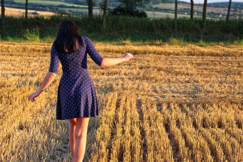Woman walking on a mown field at sunset