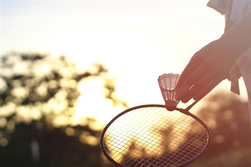 Holding badminton racket at sunset