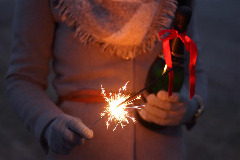 Woman holding champagne and a lit sparkler
