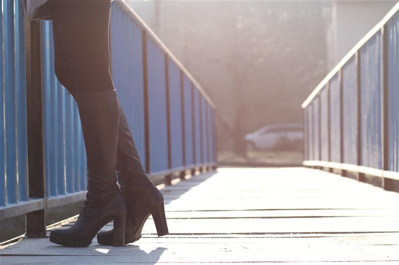 Woman in high heel boots on the bridge