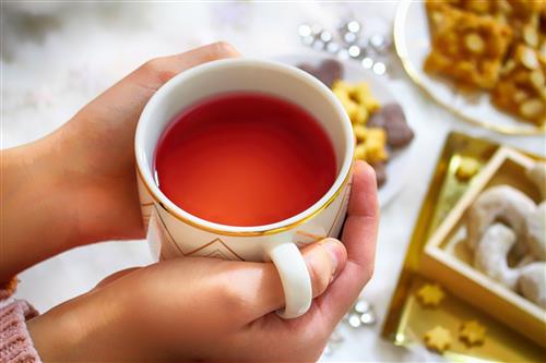 Holding a cup of tea and christmas sweets