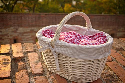 White picnic basket on brick wall at sunset
